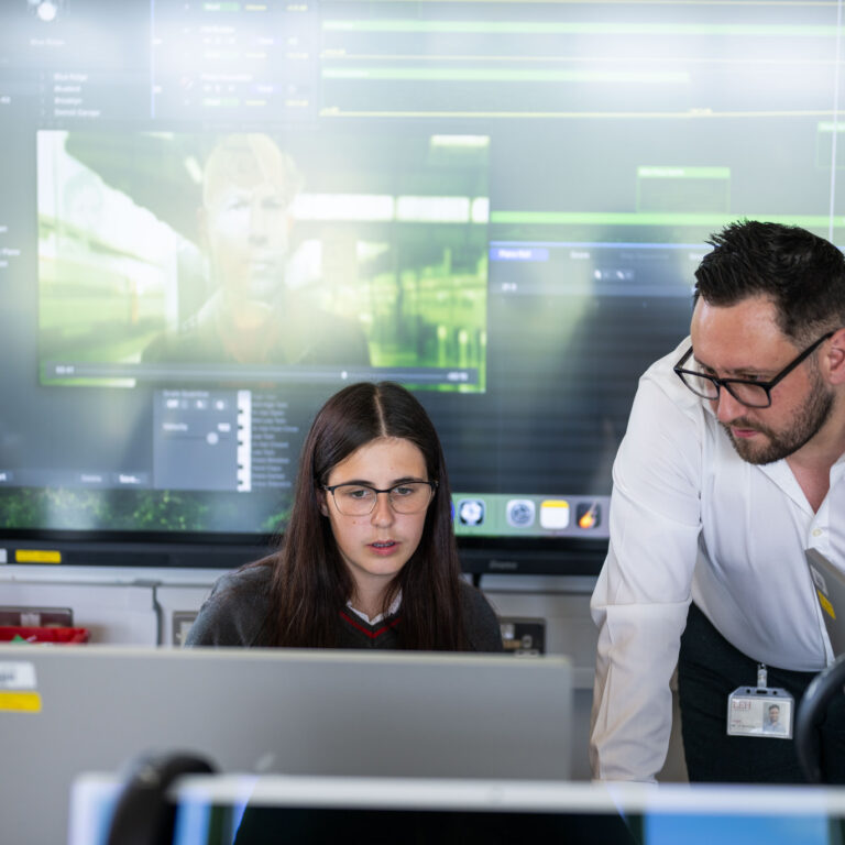 Teacher helping pupil at a computer