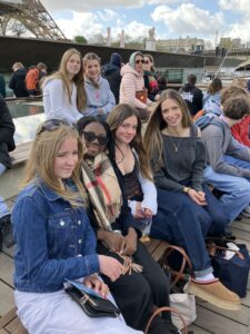 Group of friends on a Seine boat tour in Paris, with the Eiffel Tower in the background.