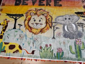 Colorful children's drawing with a gray elephant, a lion, and a giraffe among bright orange, yellow, and green backgrounds and scattered flowers and plants.