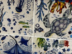 Collaged panels of colorful underwater drawings, featuring a blue-green sea turtle, coral, jellyfish, fish, and bubbles on fabric.